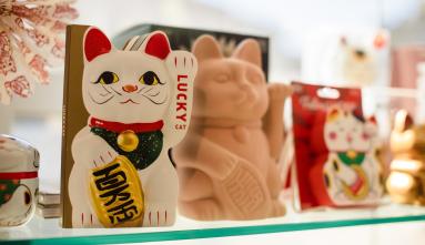 photo of JANM store shelf with Maneki neko on display and a few other items in the background